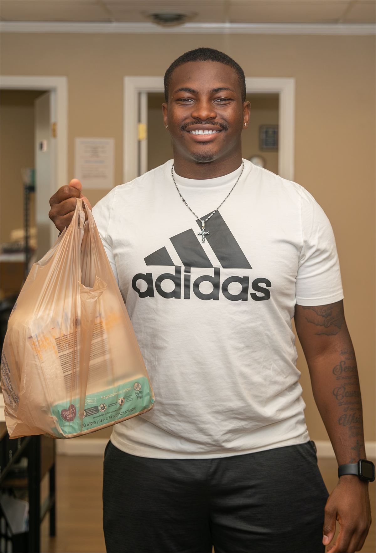 Young man smiling while holding a bag of diapers during a Diaper Day event
