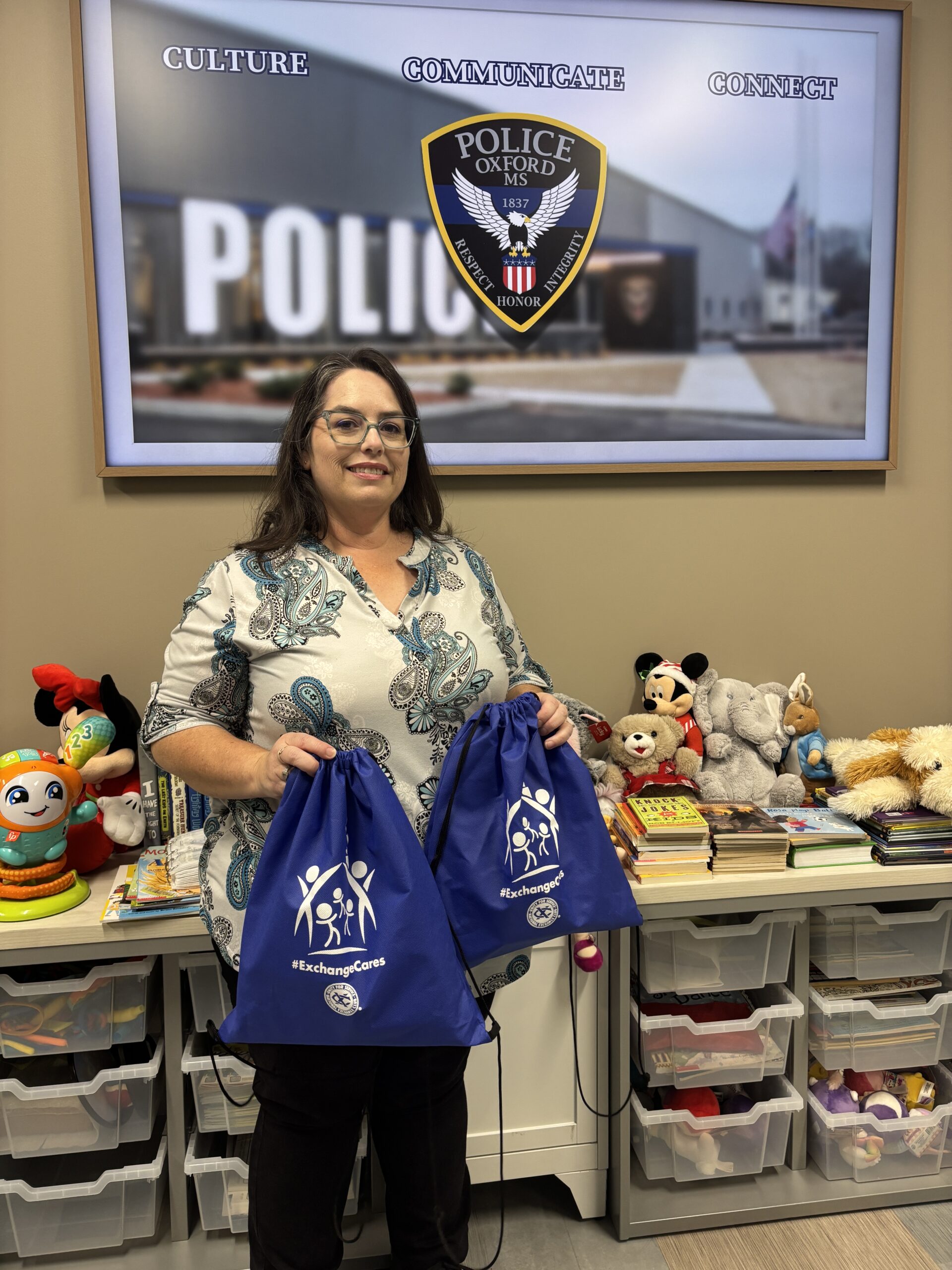 Denise standing with Exchange Cares bags at the Oxford Police Department